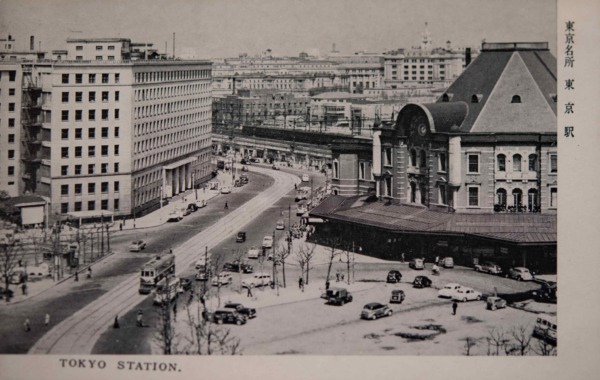 【35】帝都の象徴、東京駅。東京停車場（東京駅）は、日清戦争や日露戦争の停滞を経て、明治41年着工した。近代建築の父と呼ばれる辰野金吾が設計を手がけ、赤煉瓦と白い花崗岩を組み合わせた様式は「辰野式」と呼ばれる。1914年（大正3年）開業。コンクリートを多用したレンガ造のため、関東大震災では大きな損傷もなかったという。しかし1945年（昭和20年）の空襲で、耐火に優れた鉄骨煉瓦造の外観は残ったものの、ドーム屋根や内装はが焼失。戦災復旧工事で3階建駅舎が2階建にされ、焼失した壮麗なドームは八角形の寄棟となった。絵葉書の左に写るのは、今はなき旧国鉄本社ビル新館。1963年（昭和38年）竣工。新館は地上9階・地下3階で運輸省・国鉄本社の中枢が入った。ルネッサンス様式の優美な旧館は大戦中、空襲対策として1トン爆弾に耐える耐弾層を設置し、窓に木製の爆風避を設置し、外壁を迷彩塗装する工事が行われたという。【35】1963年（昭和38年）頃・東京名所東京駅