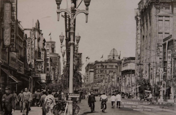 【25】戦争介入で軍隊が行進した銀座。日本が戦争へ介入するに伴って銀座もその影響を受けるようになる。戦局の悪化に伴い1940年（昭和15年）に贅沢品の製造販売禁止令（七・七禁令）や電力制限による広告灯・ネオンサインの消滅、1941年（昭和16年）洋風の店名が禁止され、現在も残る文壇バー「ルパン」（菊池寛、里見弴、泉鏡花、永井荷風、川端康成、久米正雄、林芙美子、太宰治が通った）は、「麺包亭」と名乗って営業したという。 1944年（昭和19年）戦局が苛烈を極め、劇場・料理店・待合芸妓屋・バーが閉鎖され、銀座は大打撃を受けた。その一方、軍隊の行進や、贅沢を諫める運動も街頭で行われた。街灯や都電のレールが取り外され軍事物資に提供され、食糧不足から畑を耕す人も現れた。【25】1940年（昭和15年）頃・（大東京）帝都随一の商店街 銀座通