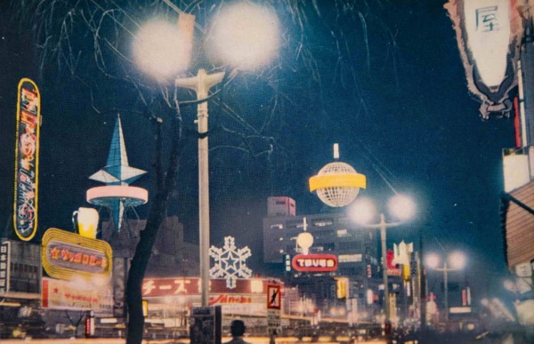 【31】ネオン広告塔が夜の銀座を照らす。銀座の夜を華やかに彩った高層ネオンは、1953年（昭和28年）晴海通りに面した不二越ビル（現在のアルマーニ銀座タワー）屋上に登場した森永ミルクキャラメルの広告塔。通称「サボテン」と呼ばれた地球儀。「ヒトデ型」のナショナル（現･パナソニック）は、当時3階建だった鳩居堂ビル屋上に、建物の2倍以上という巨大な大きさが話題に。銀座の名物になり、絵葉書や映画にも登場した。1963年（昭和38年）三愛ドリームセンターが完成すると目立たなくなって姿を消し、鳩居堂ビルも三愛と同じ高さのビルに改築された。雪印ネオンサインは、三愛ドリームセンタービルができる場所にあり、雪の結晶をまばゆく演出した。【31】1955(昭和30年)頃